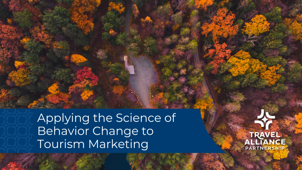 An aerial view of a forest in fall, with trees bearing yellow, orange and red leaves. A house or barn structure is in the middle. Overlaid on the image is a blue banner with the title "Applying the science of behavior change to tourism marketing" and the Travel Alliance Partnership logo is next to that.