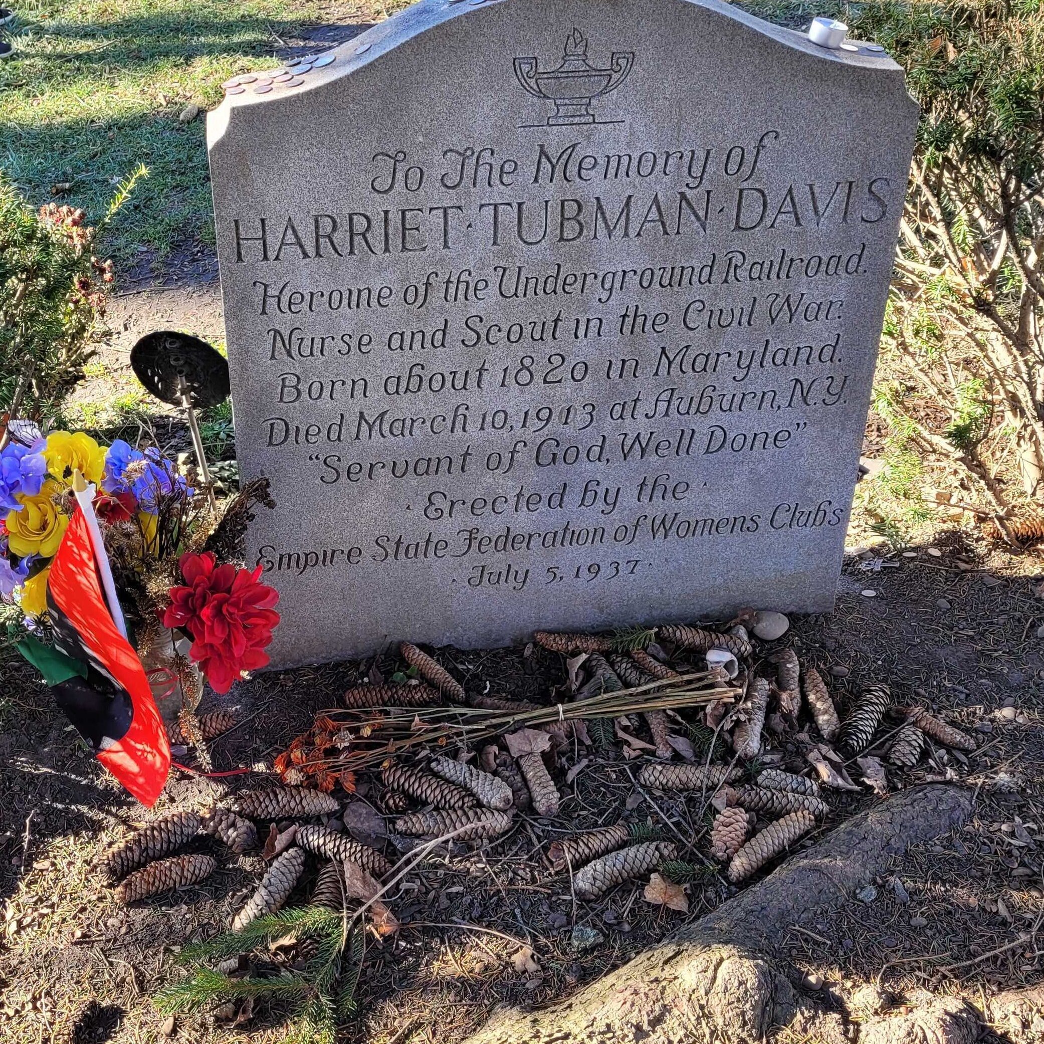 gravestone with the name Harriet Tubman Davis with memorial inscription decorated with red ribbons and flowers with pinecones at the base